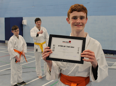 Young man in martial arts uniform holding a certificate