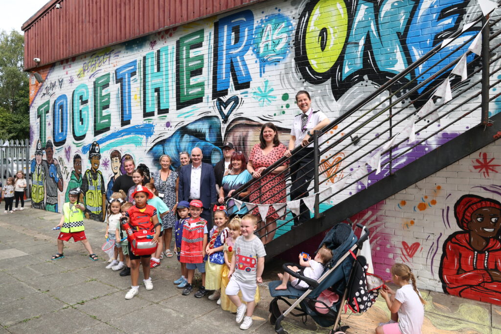 PCC Emily Spurrell, MVRP Director Georgie Garvey, St Helens councillors and families posing next to the Together as One mural