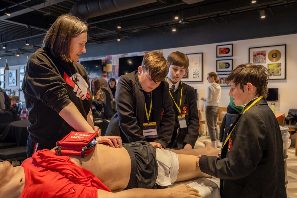 Young people learning how to stop a serious wound by applying pressure. 