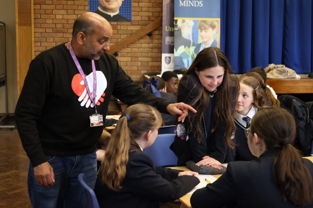 Nikhil Misra teaching compression techniques to a group of pupils using small cushions. 
